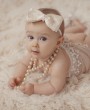 Ivory satin and gold lace bow decorated with stunning pearl trim on a soft elastic headband