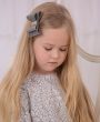 Shimmery grey layered bow with long rhinestone button on an alligator clip.